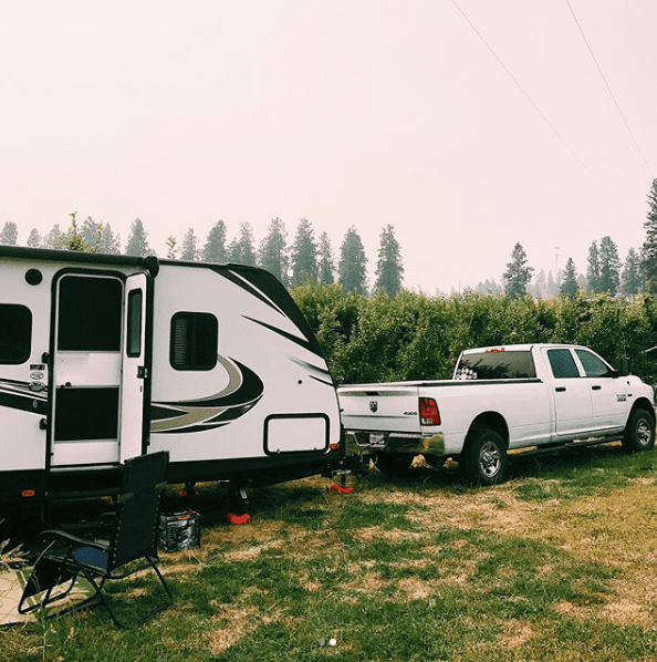 White truck hitched to travel trailer at campground