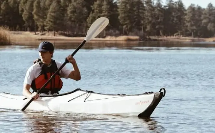 Boy paddling kayak on lake