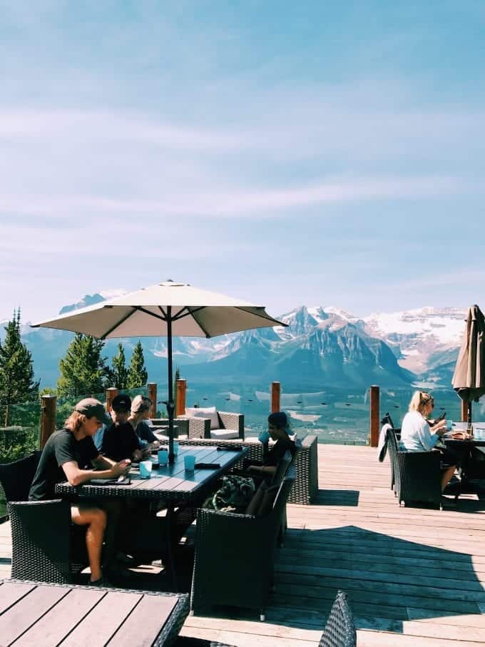 Family eating lunch at table on outdoor patio with view of mountain peaks
