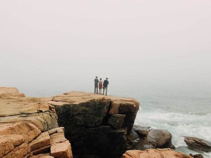3 hikers standing near edge of rock wall near Main ocean
