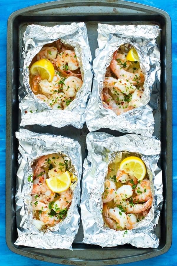 Four foil packets filled with shrimp, lemon, and butter.
