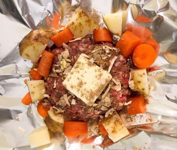 Beef, carrots, and potatoes inside foil packet for campfire pot roast dinner