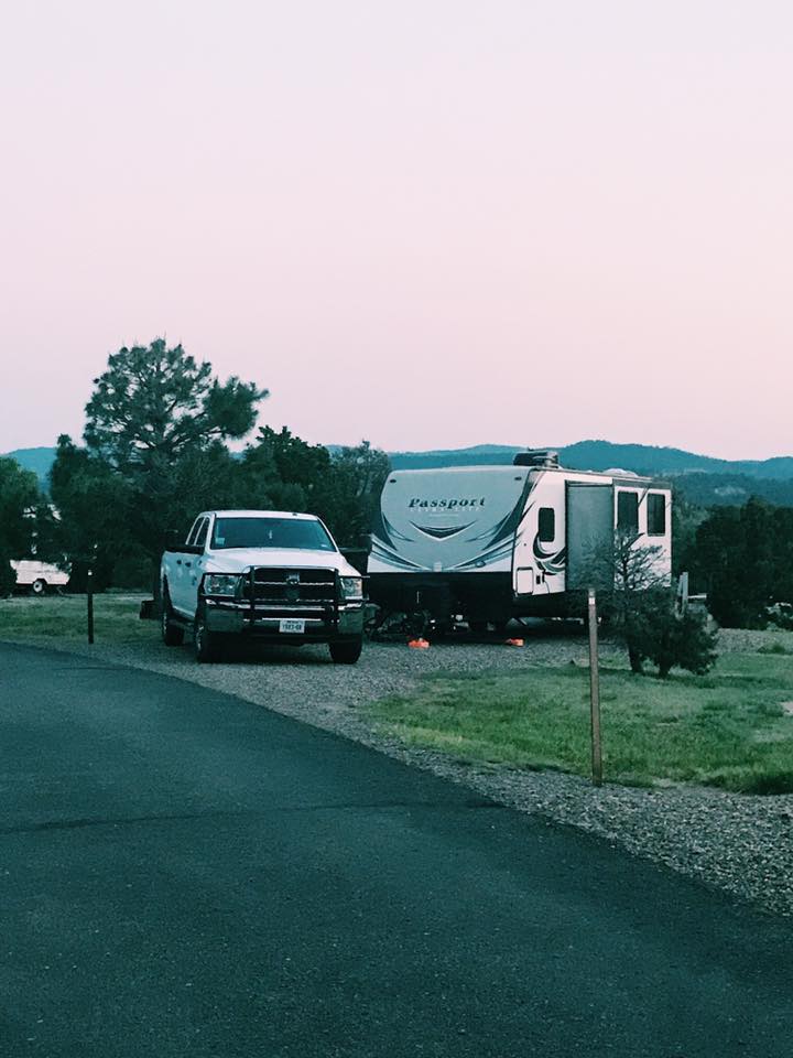 White truck and travel trailer parked at a campground