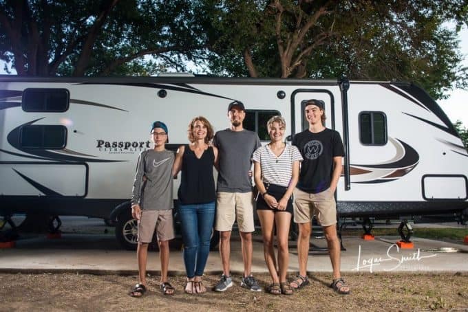 Family of five standing in front of their new travel trailer.