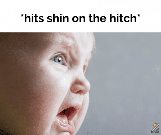 Close up of face of sad baby with text 'hits shin on the hitch'