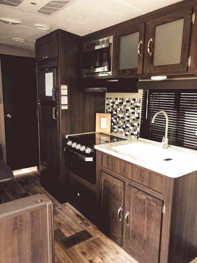 Stove, sink and fridge inside Keystone Springdale travel trailer.