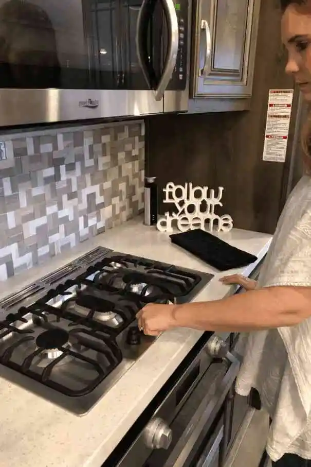 Woman turning on stove inside RV