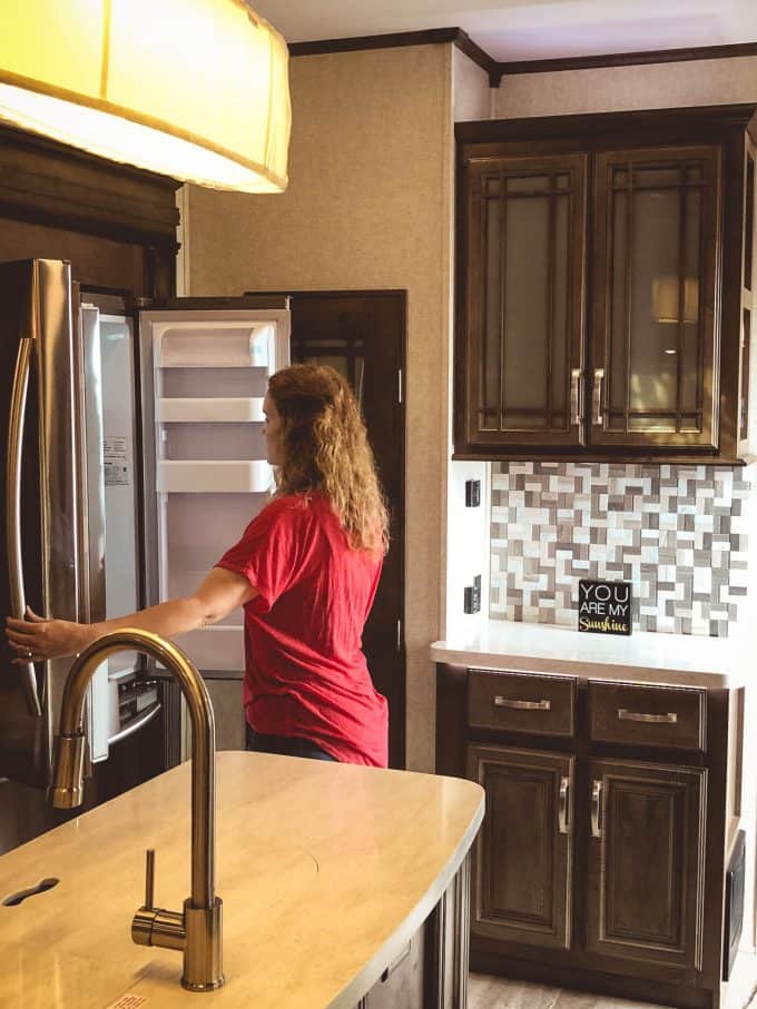 Woman looking at refrigerator in the 2019 Keystone Montana 3561RL Fifth Wheel