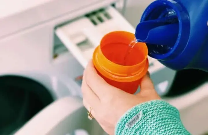 Woman pouring detergent into cap to do laundry while on RV road trip