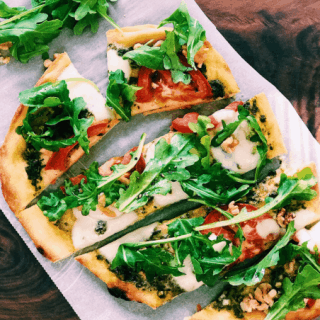 Sliced Naan pizza with arugula and tomatoes at campsite