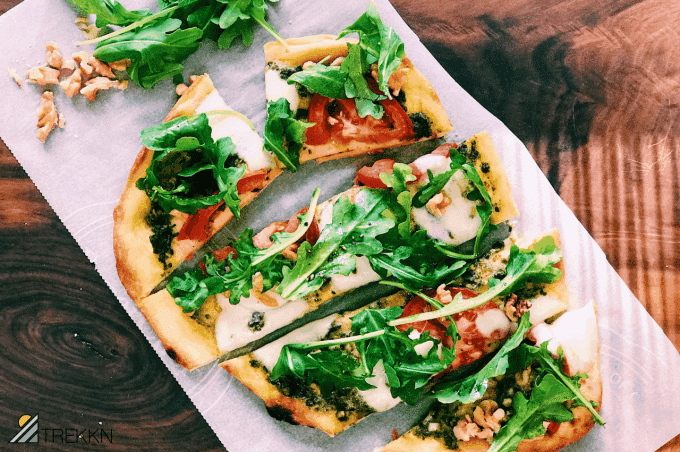 Sliced Naan pizza with arugula and tomatoes at campsite