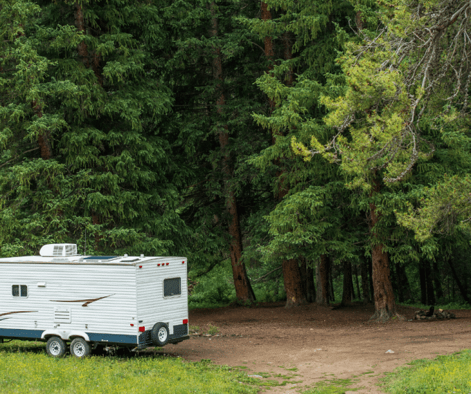 RV with solar panels on roof parked in wooded area