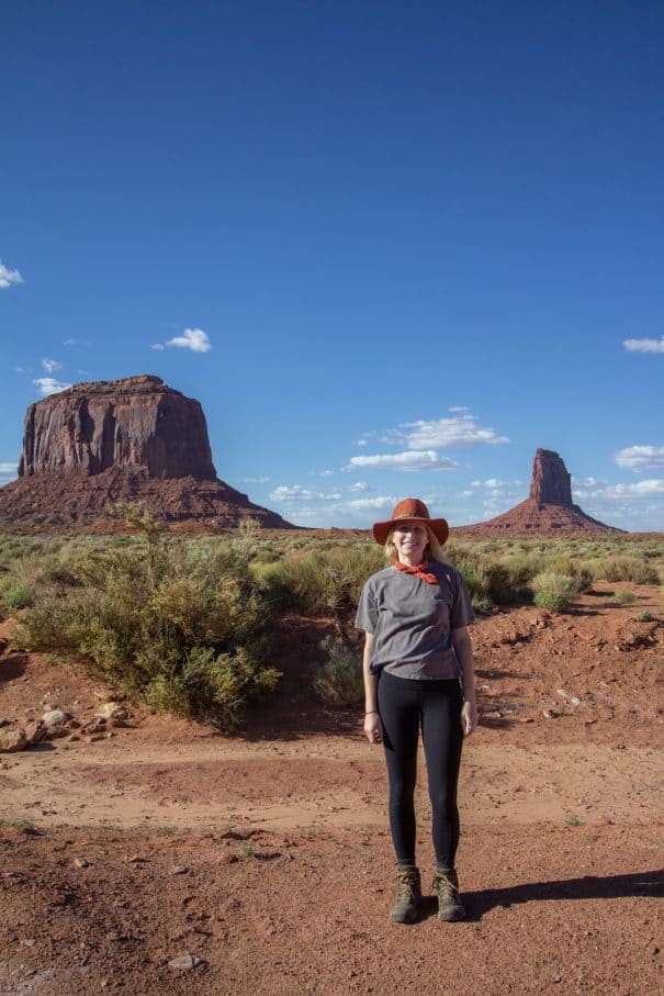 Woman in hat hiking in front of rock spires at Canyonlands National Park