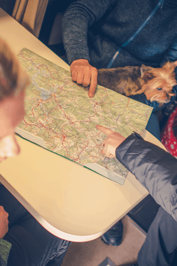 Group inside RV looks at a map to plan their travels with their little Maltese dog.