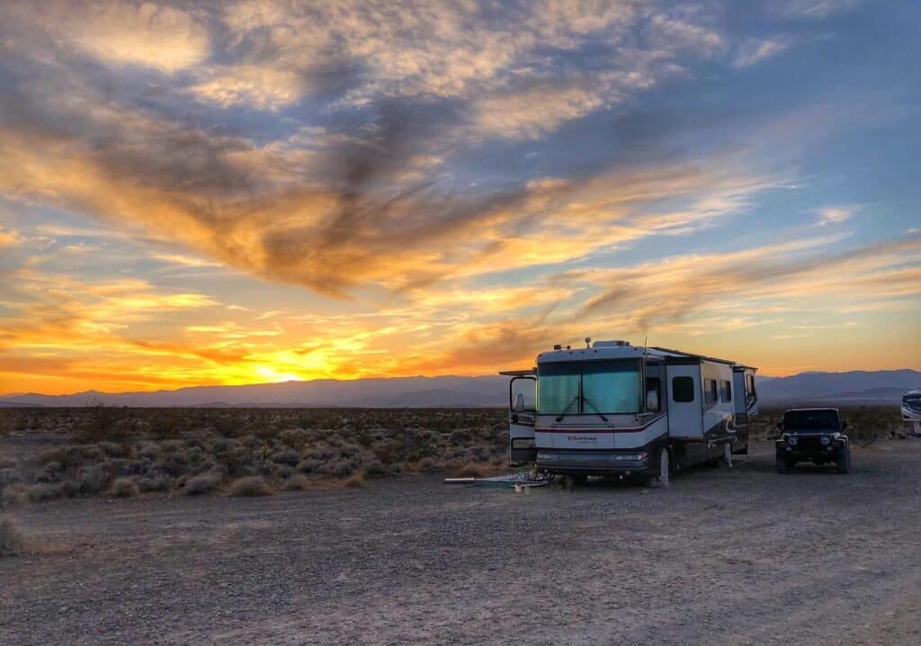 Large RV parked in desert at sunset
