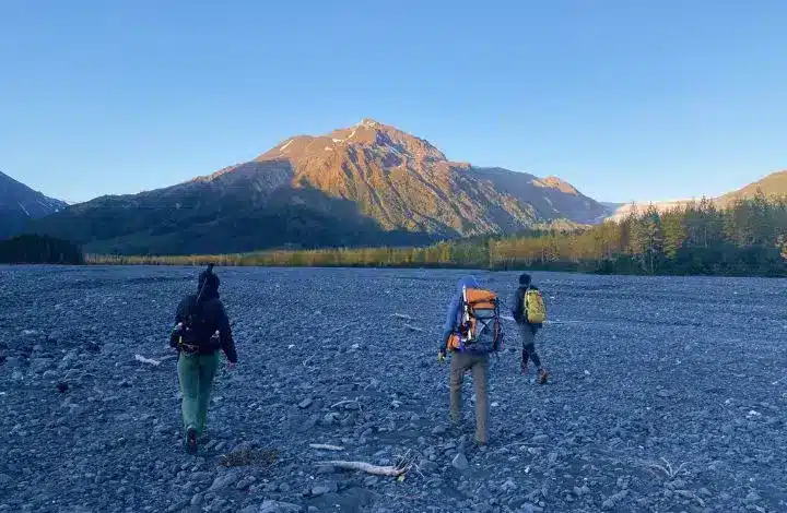 Three hikers carrying backpacks during day hike in Alaska