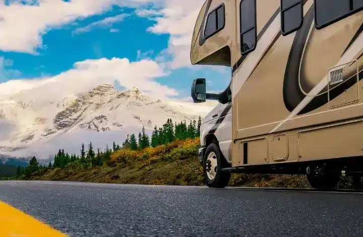 Motorhome RV being driven on open road with mountains and trees in background