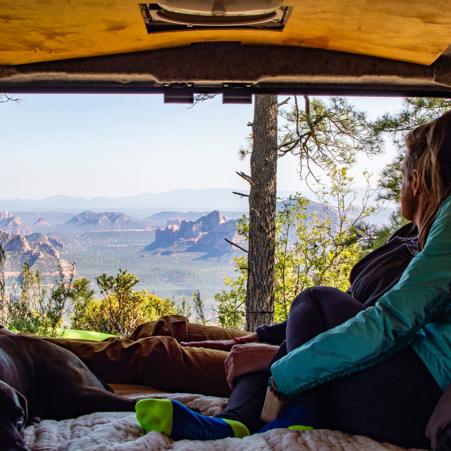 Woman and man looking out back of campervan toward mountains