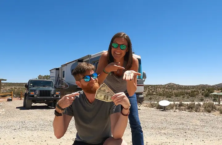 Man and woman pointing at money to indicate tiny living in RV helped them reach financial freedom