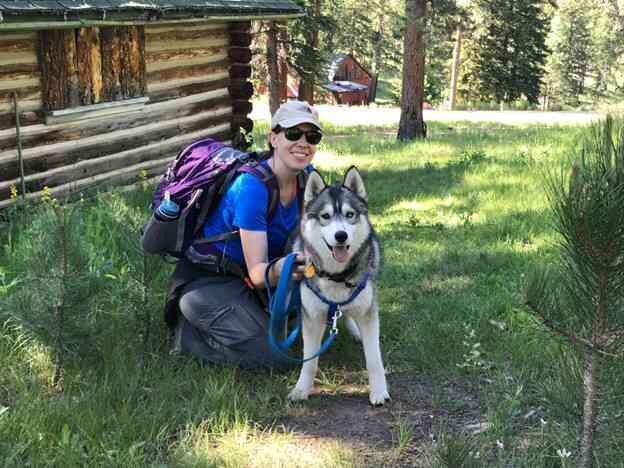 Woman preparing to go camping with Husky dog by her side.
