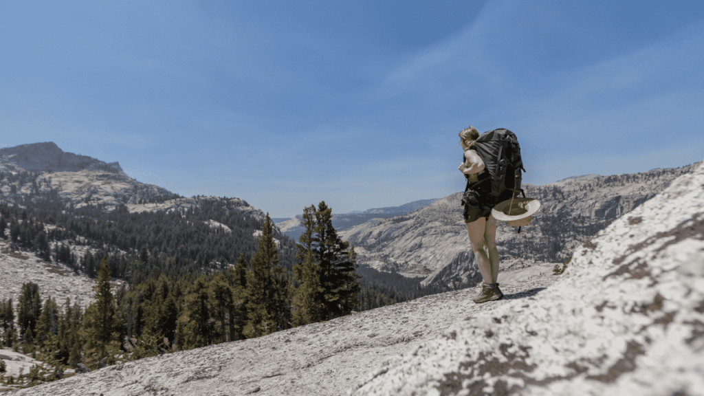 Woman with backpack standing on mountain during solo hiking trip
