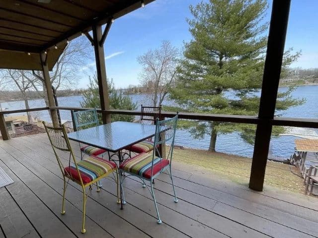 Patio chairs and table on deck of rental cabin near lake