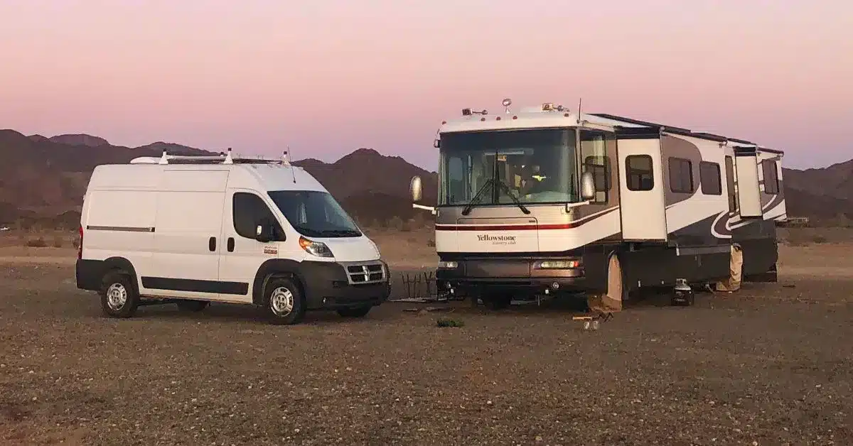 White Campervan and Class A RV parked in boondocking area at dusk