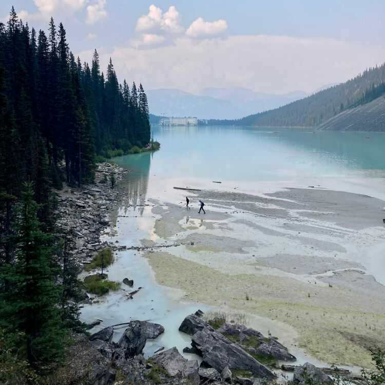 Two Hikers trekking along shore of Lake Louise in Banff National Park in Canada