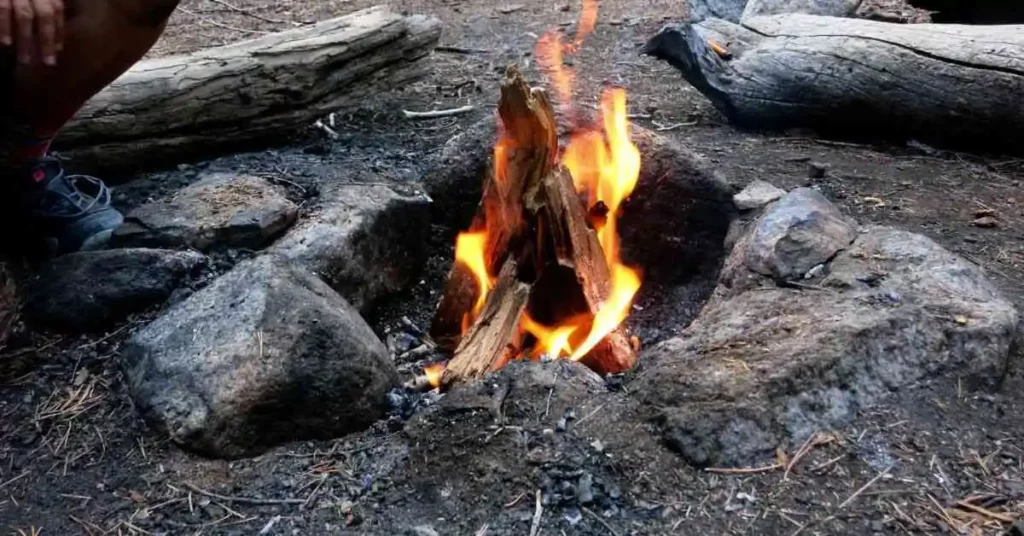 Small cone shaped fire inside campfire ring