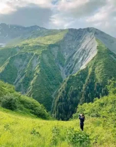 Woman hiking on lush green grass mountain in Alaska