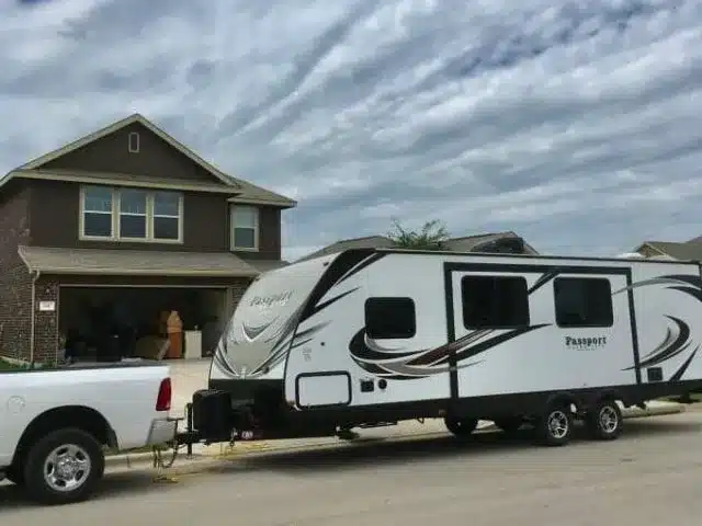 Travel trailer parked in front of house as family prepares for full-time RV living.