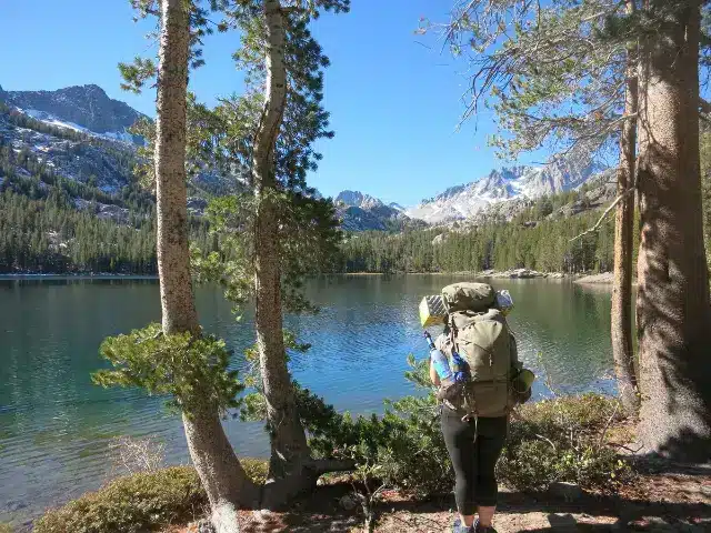 Woman standing near waters edge during backpacking trip in the Sierra Mountains