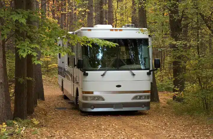 Class A motorhome parked at campsite surrounded by fall foliage