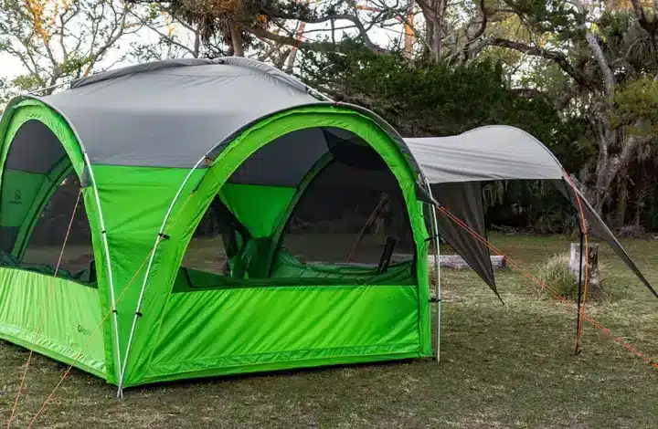 Green and grey outdoor gazebo with awning pitched at campsite.