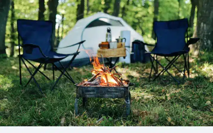 Small campfire set in front of outdoor chairs and tent