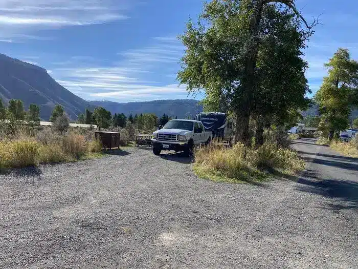 White truck and fifth wheel parked near trees and picnic table at Mammoth Campground in Yellowstone National Park