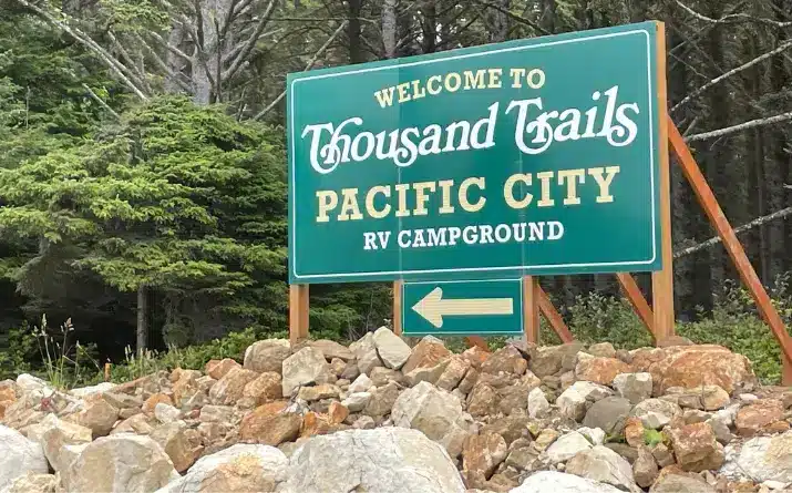 Large green sign with words 'welcome to thousand trails pacific city rv campground'