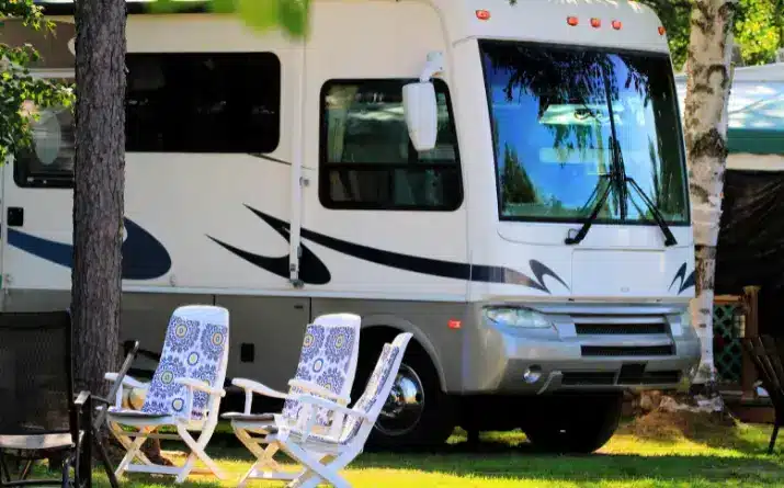 Lounge chairs next to Class A Motorhome parked at campsite