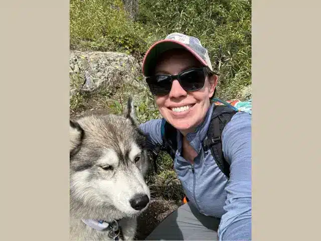 Smiling solo hiker with her husky dog.
