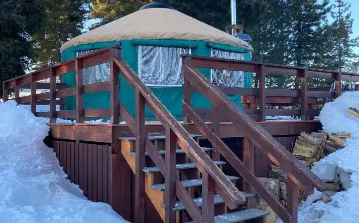 Green yurt surrounded by snow