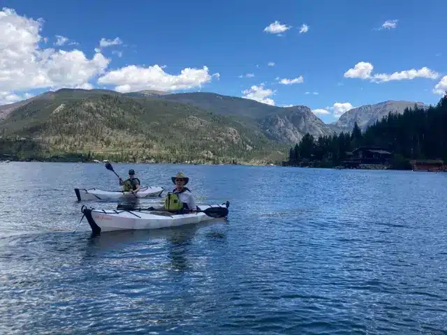 Woman and man in separate kayaks on Grand Lake at Rocky Mountain National Park.