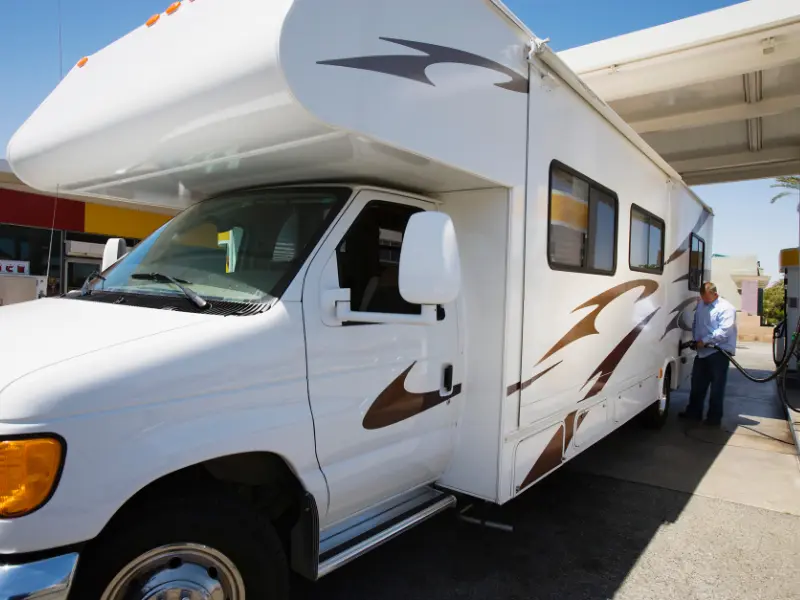 Man pumping fuel, a main cost of RV living, into his RV.